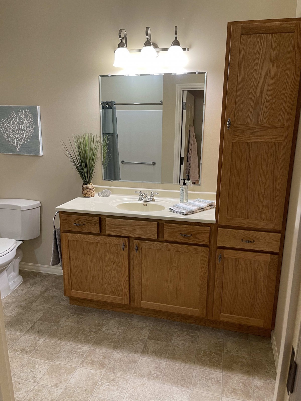 A cozy bathroom with wooden cabinetry, a large mirror, and essential fixtures.