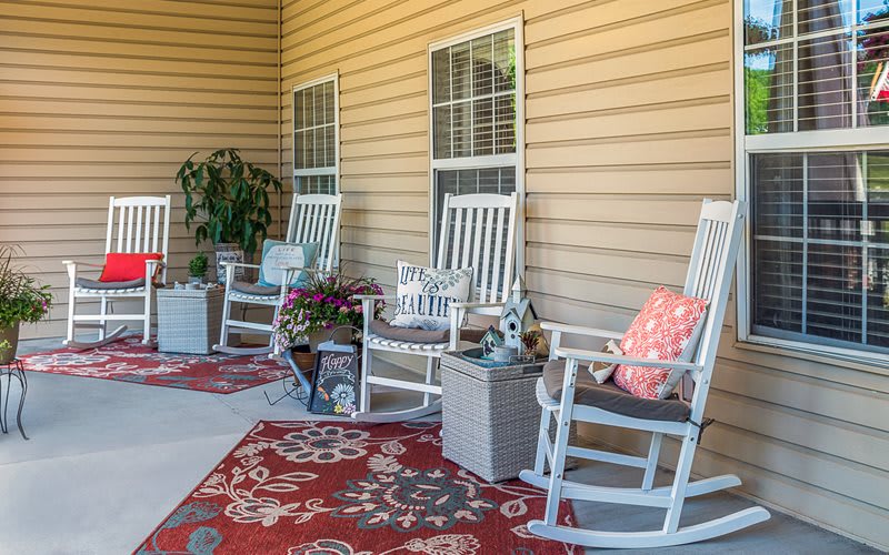 A cozy porch with white rocking chairs and decorative plants.