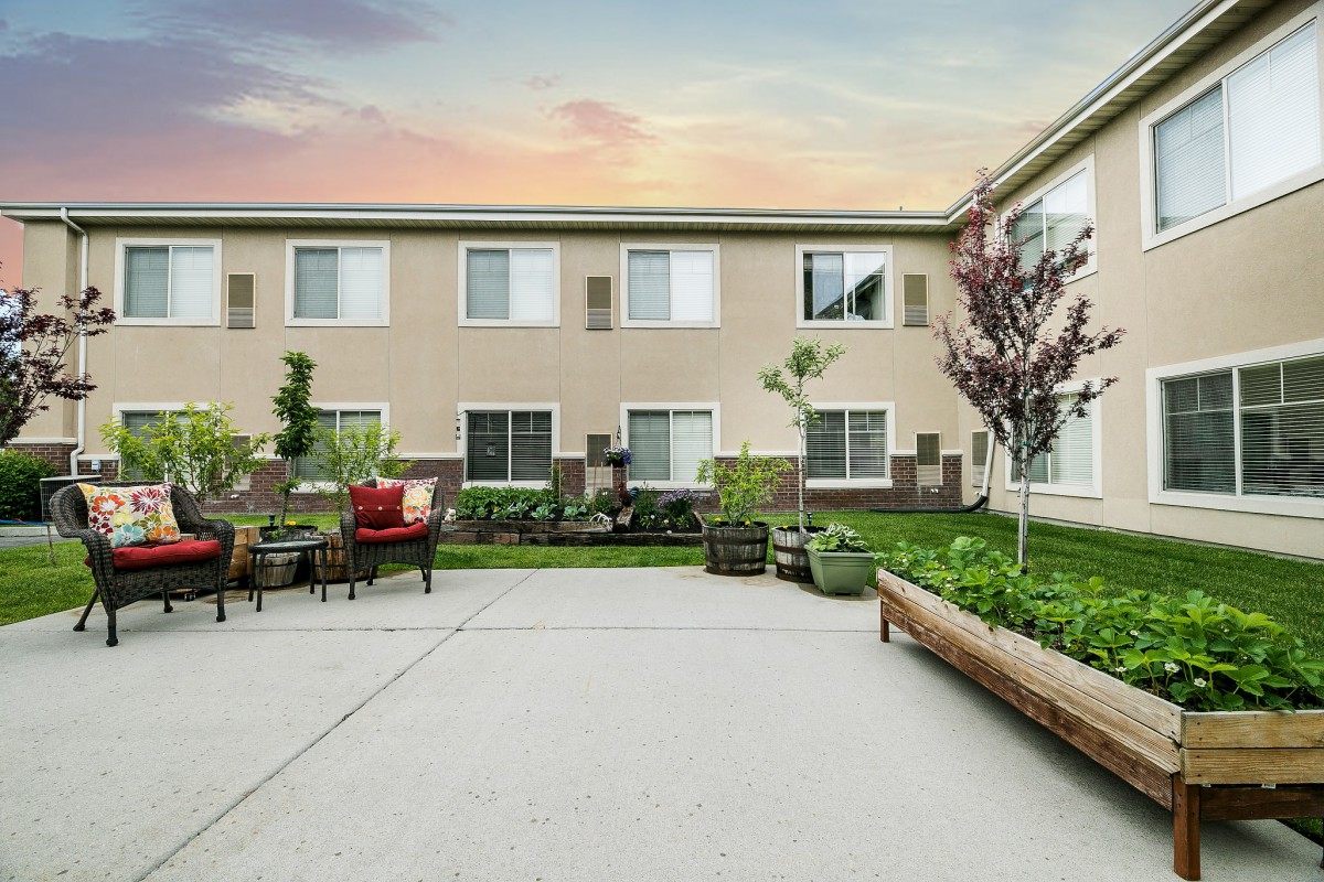 A serene courtyard with benches and a well-maintained garden at sunset.