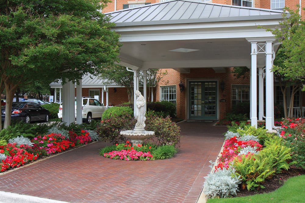 A welcoming entrance with a beautifully landscaped garden and statue under a covered walkway.