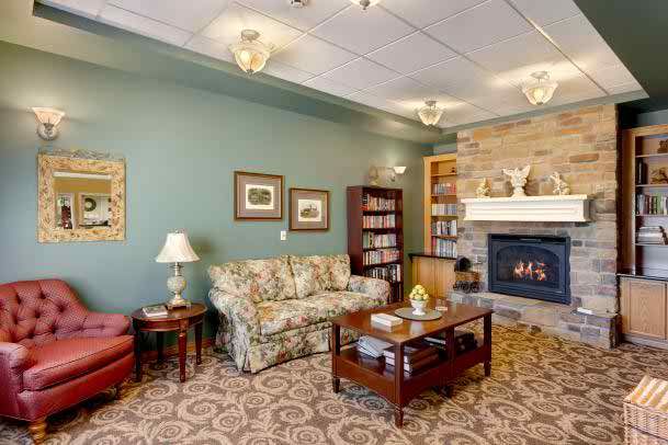 A cozy living room featuring a fireplace, bookshelf, and floral-patterned sofa.