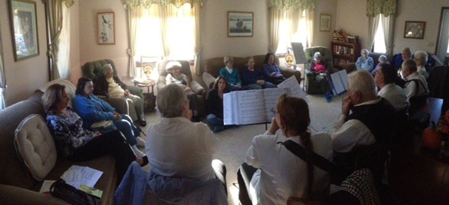 A group of people sitting together in a living room, engaging in a social activity.