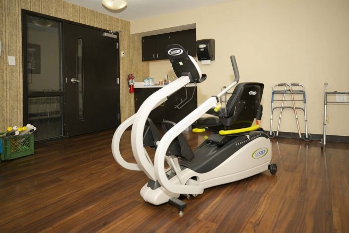A recumbent cross trainer positioned in a room with wooden flooring.