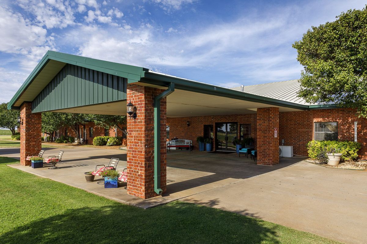 A brick carport providing shade over a driveway under a clear blue sky.