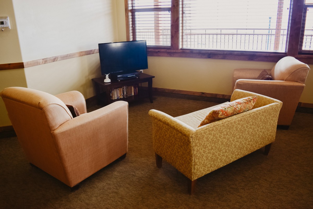 A cozy living room with a sofa, armchair, and a television.