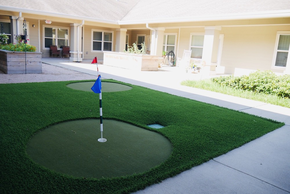 An outdoor courtyard featuring a small putting green with colored flags.