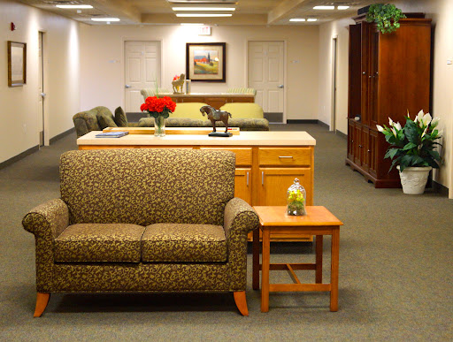 A cozy office lounge area featuring a patterned couch, coffee table, and decorative plants.