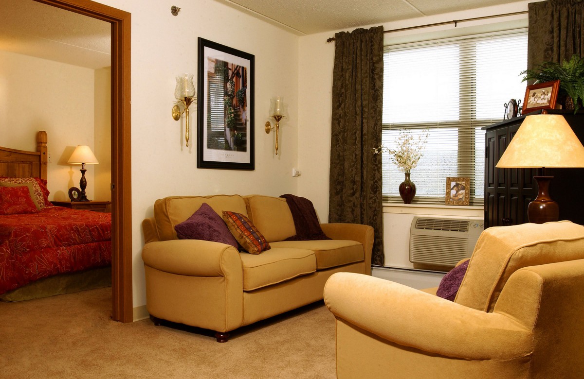 A cozy living room with beige sofas, decorative cushions, and framed artwork on the wall.
