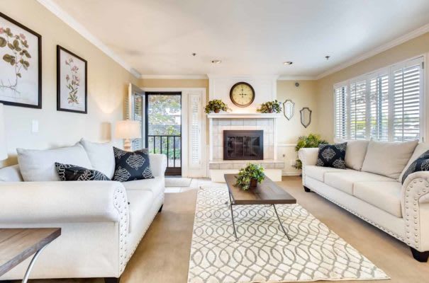 A modern living room with white sofas, a central fireplace, and a stylish coffee table.