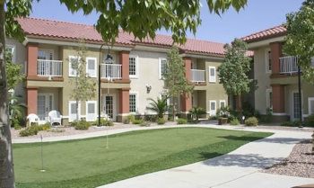 A residential apartment building with a neatly maintained lawn and surrounding greenery.