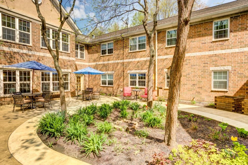 A charming courtyard with lush greenery and comfortable outdoor seating in front of a brick building.
