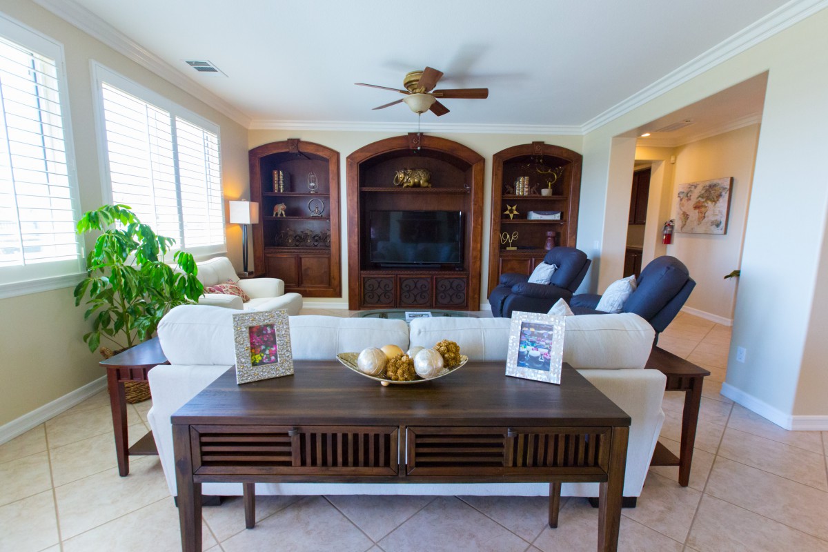A well-furnished living room with a large sofa, armchairs, and built-in shelves surrounding a TV.