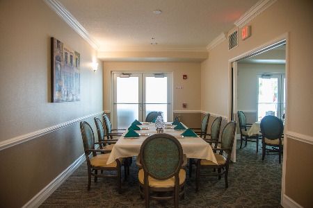 A formal dining room with a neatly set table surrounded by elegant chairs.