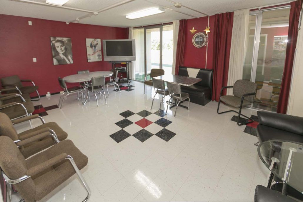 A modern room with red walls, featuring tables, chairs, and a television.
