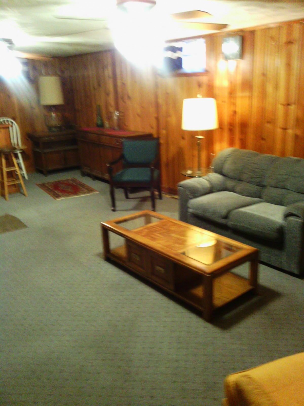Cozy living room with wood paneling and comfortable furniture.