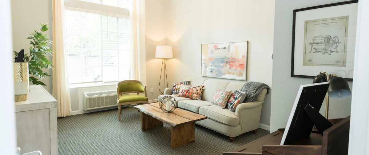 A cozy living room with a sofa, coffee table, and a stylish chair under natural light.