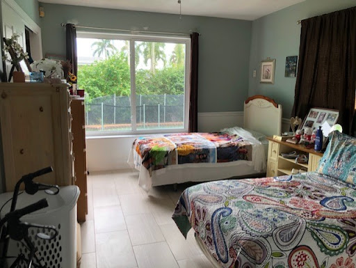 A cozy bedroom featuring natural light, colorful bedding, and a view of greenery outside.