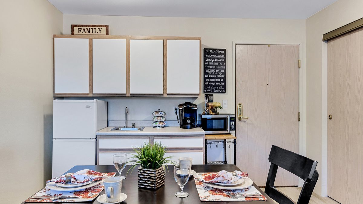 A cozy kitchen and dining area featuring a well-set table, white cabinets, and modern appliances.