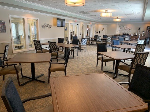 An empty dining area with neatly arranged tables and chairs, softly lit by overhead lights.