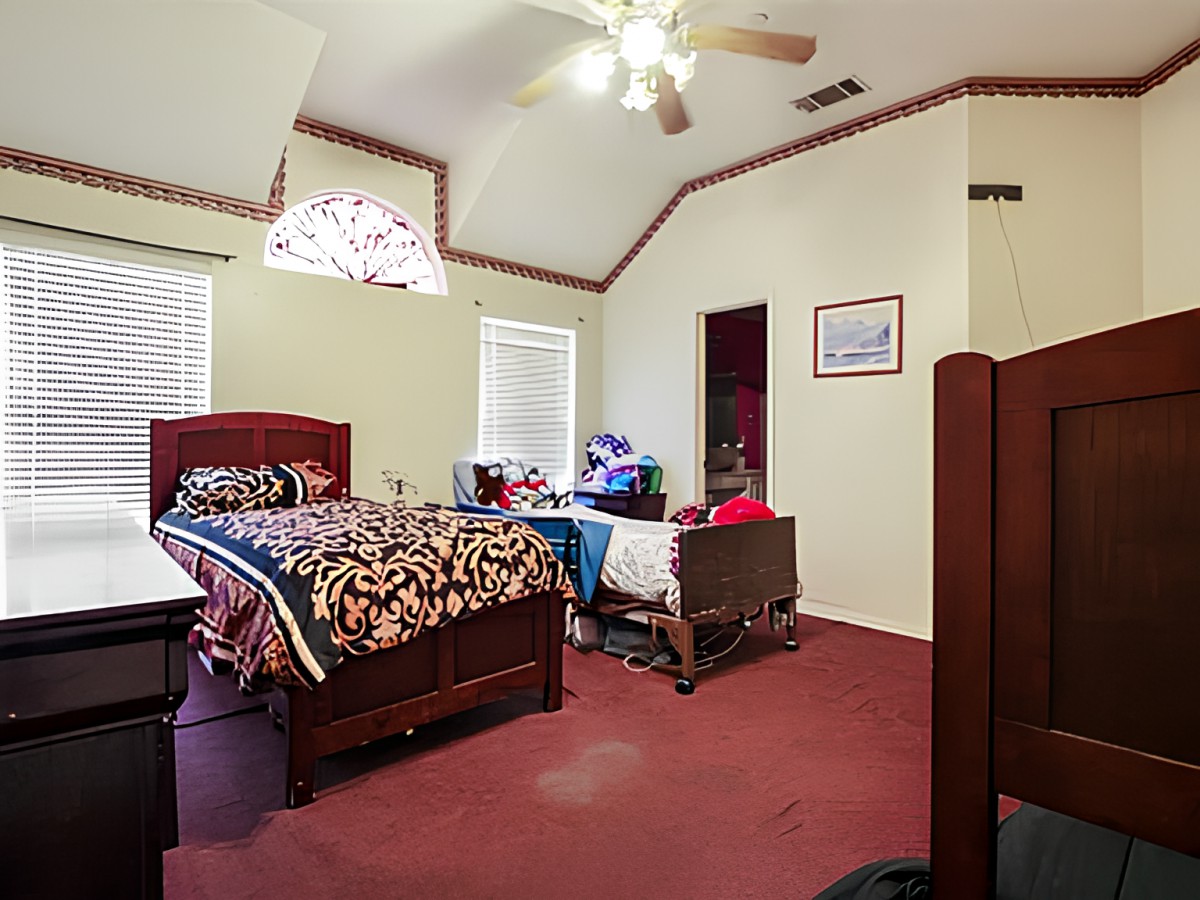 A cozy bedroom with a bed, carpeted floor, and ceiling fan.