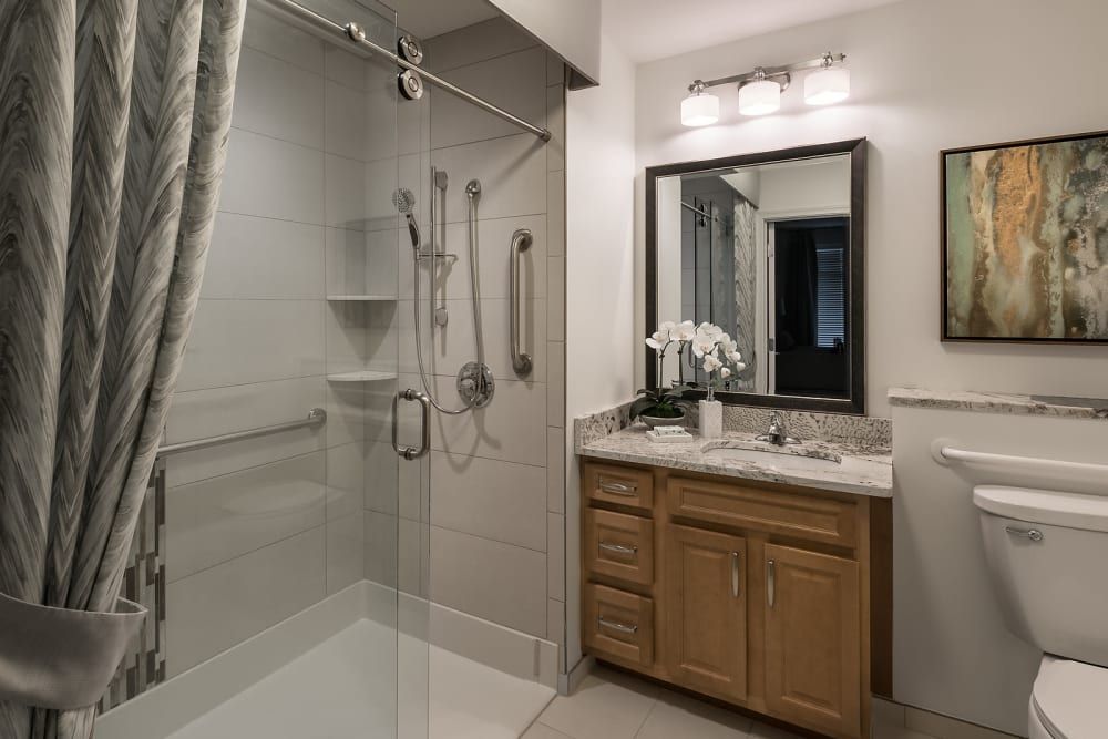 A modern bathroom with a walk-in shower and a vanity with wood cabinets.