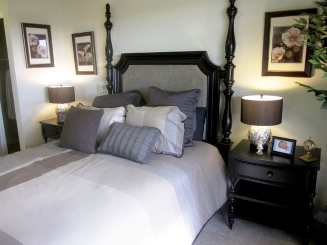 A cozy bedroom with a dark wooden bed frame and stylish decor.