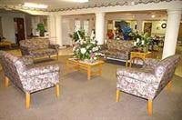 A cozy lobby area with patterned sofas, chairs, and a central table adorned with plants.