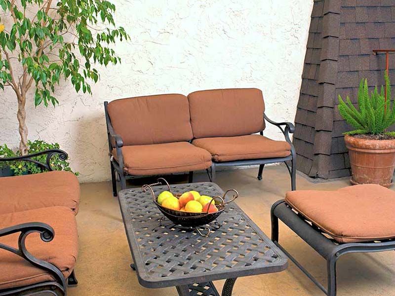 A cozy patio setup with brown cushioned seating and a table featuring a fruit bowl centerpiece.