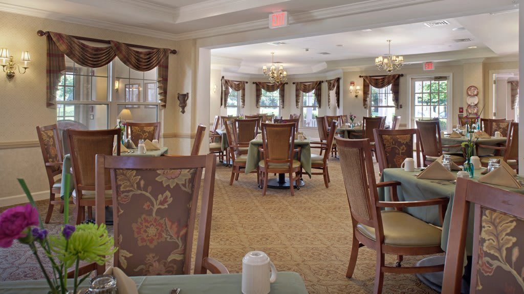 An elegant dining room with tables and chairs arranged under chandeliers.