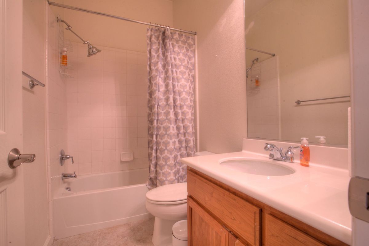 A cozy bathroom with a shower curtain, toilet, sink, and mirror.