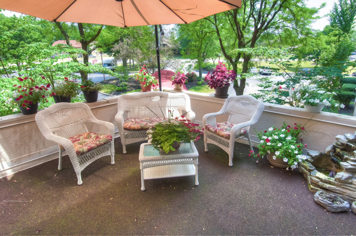 A cozy outdoor patio with wicker furniture and vibrant flowers.