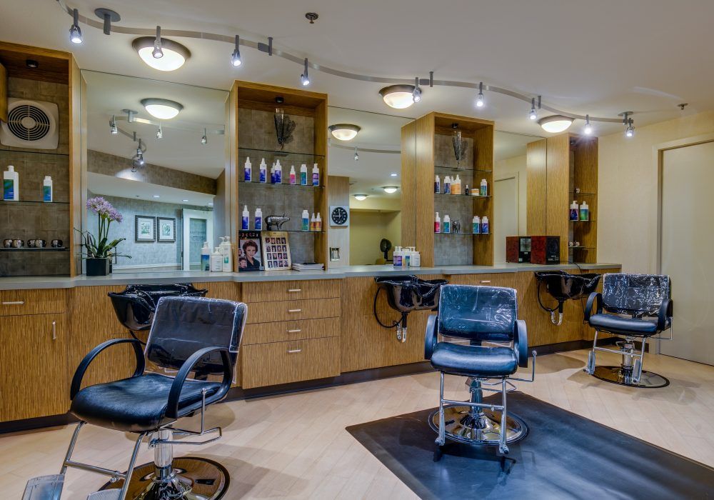 A modern hair salon interior featuring stylish chairs and well-lit mirrors.