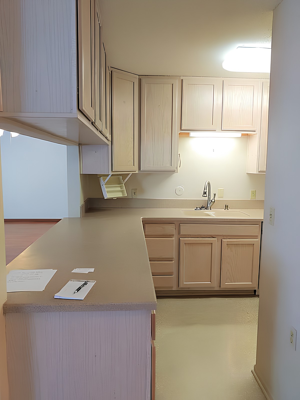 A compact kitchen with light wood cabinets and a spacious countertop.
