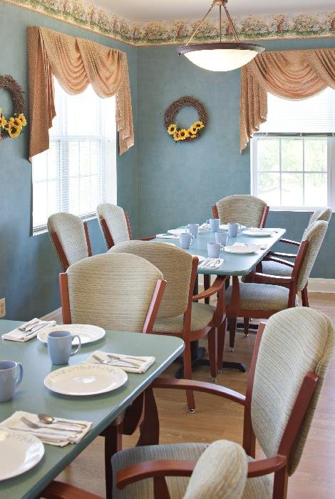 A neatly arranged dining room with table settings and decorative wreaths on the walls.