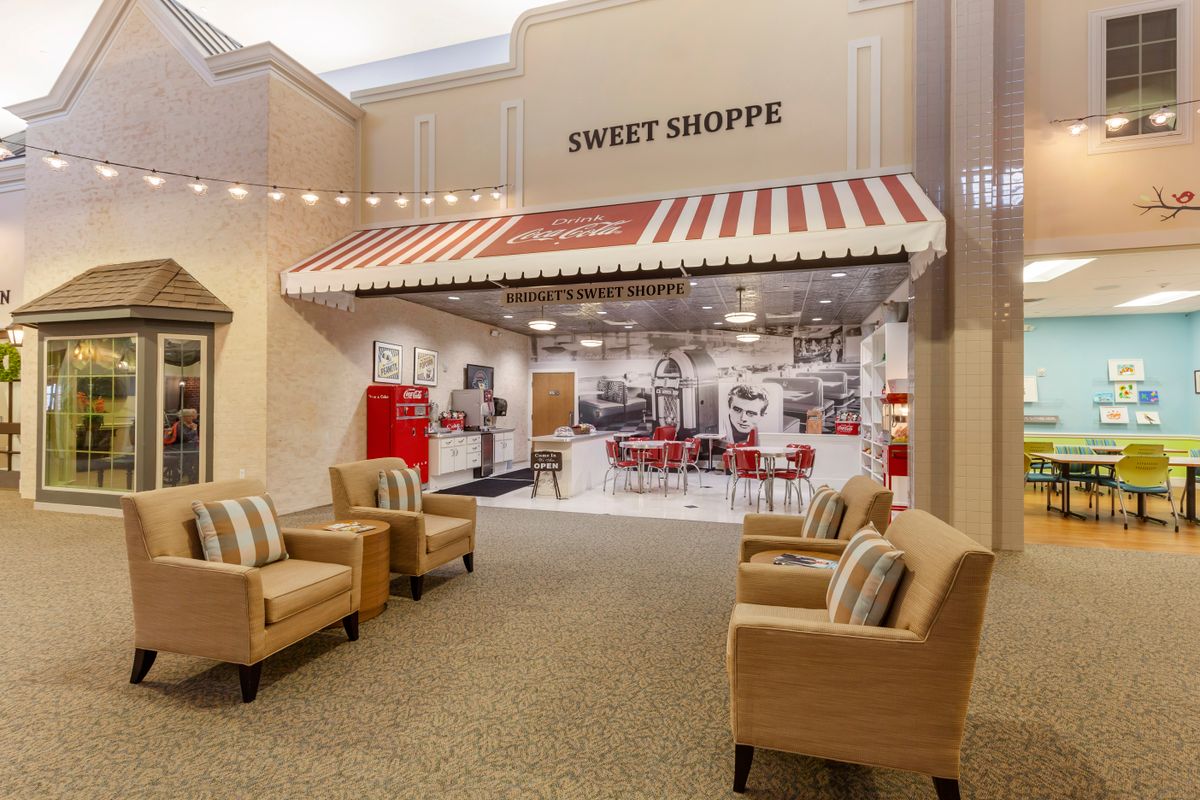 A cozy interior featuring a vintage-style sweet shop with a red and white striped awning, alongside a comfortable seating area.