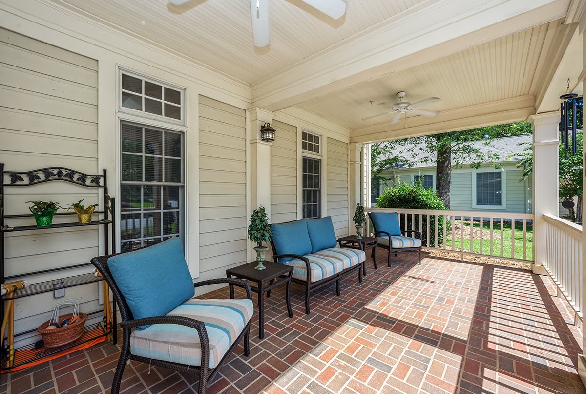 A cozy covered porch with comfortable seating and a brick floor, perfect for relaxing outdoors.