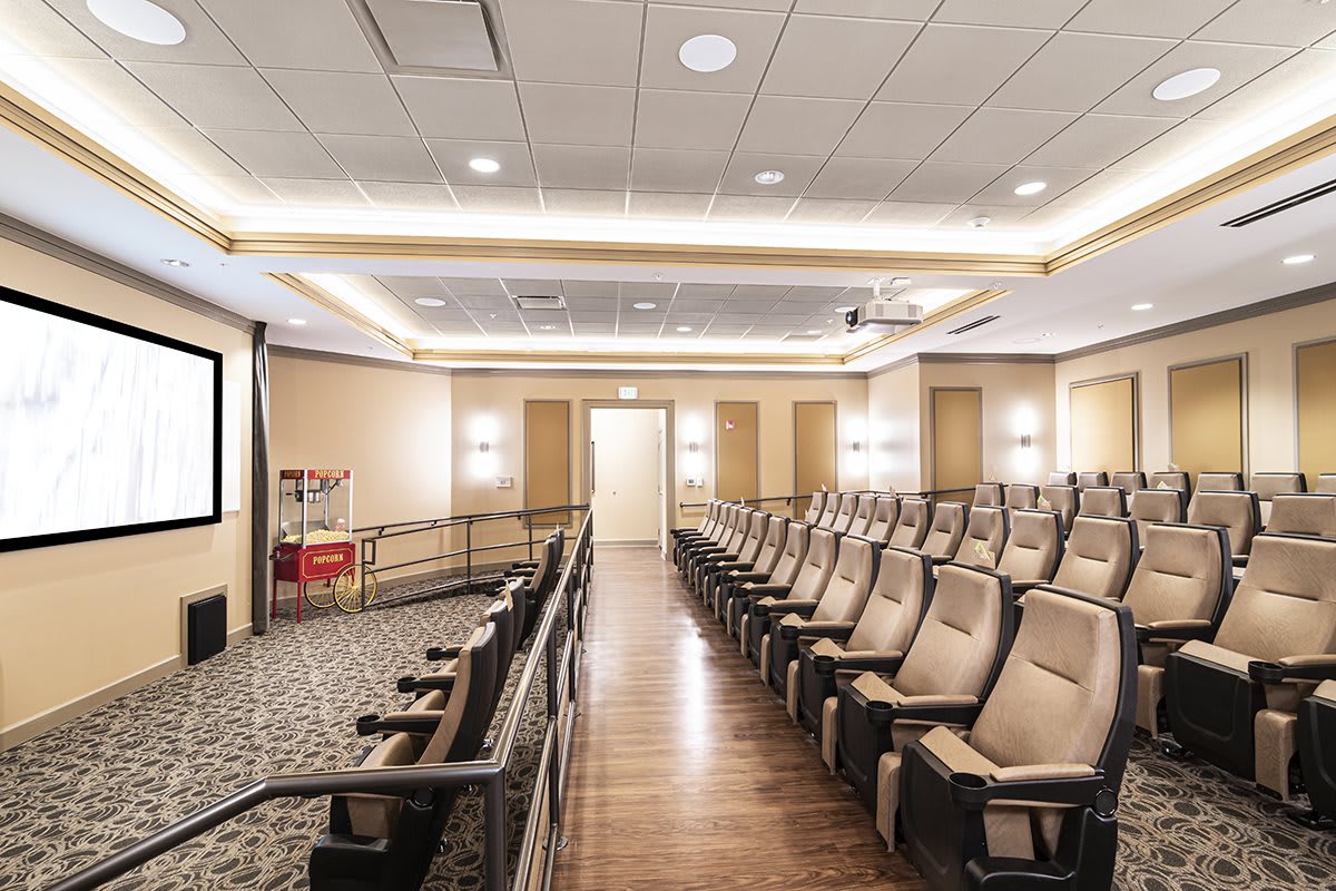 An empty auditorium with rows of comfortable seating and bright lighting.