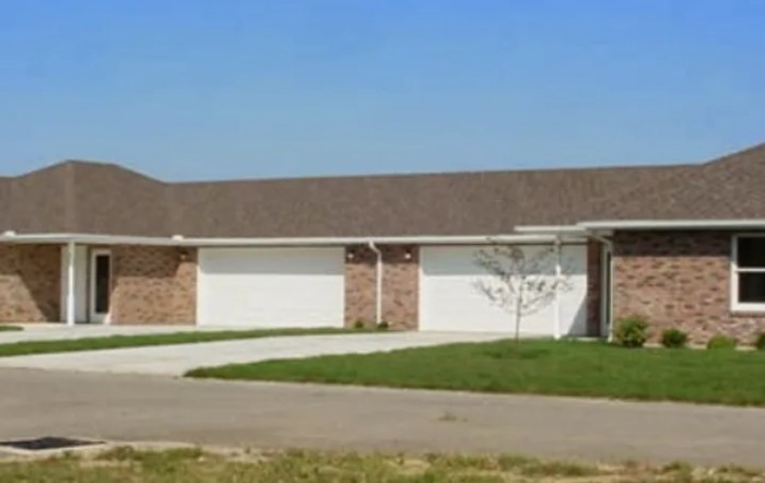 A suburban duplex with a driveway and well-maintained lawn.