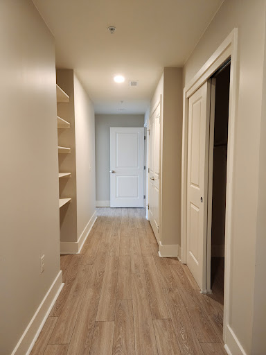 A spacious and well-lit hallway featuring shelves and multiple doors.