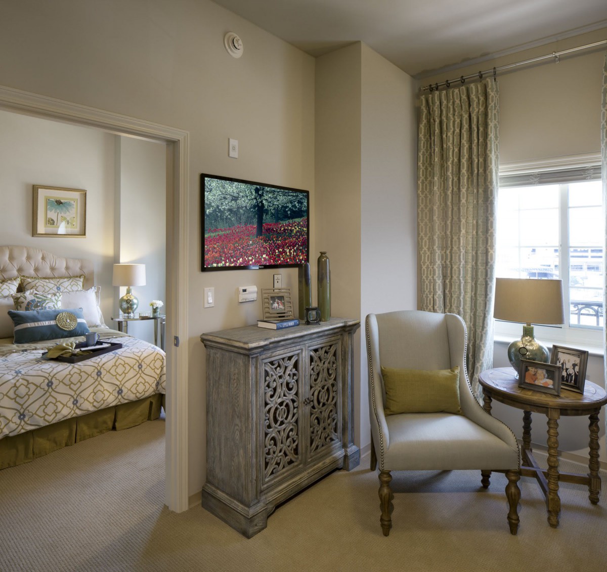 A cozy living space featuring elegant furniture and decor, with a view into a stylishly decorated bedroom.