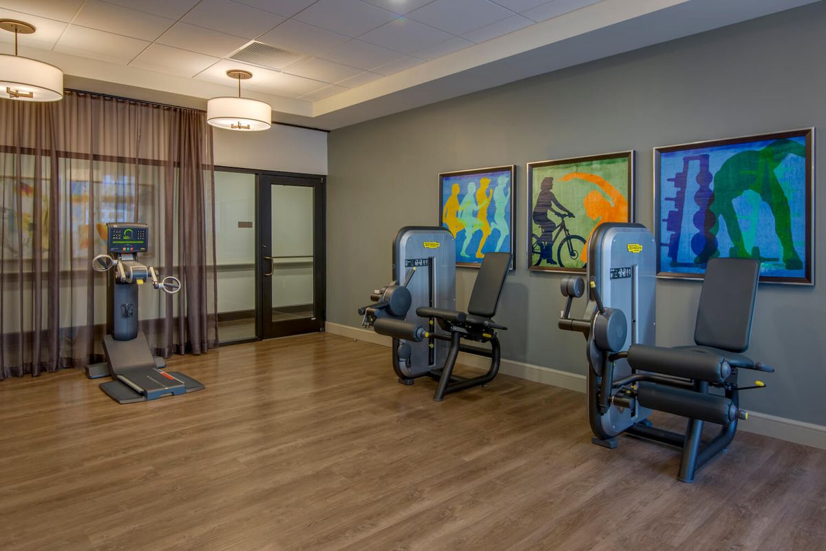 A modern fitness room with exercise equipment and colorful artwork on the walls.
