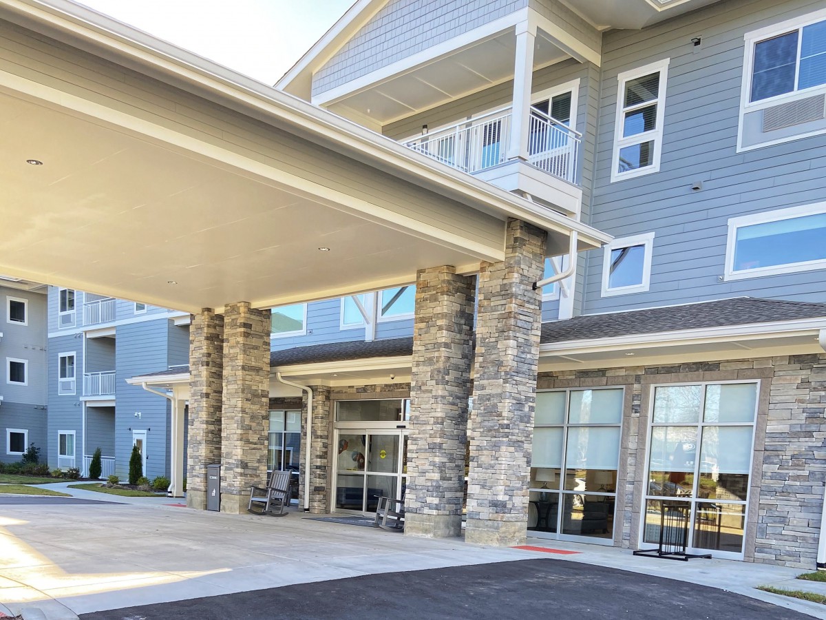 The modern building entrance features prominent stone pillars and large glass windows.