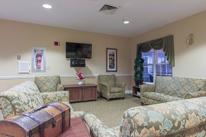 A cozy living room with patterned furniture and a wall-mounted television.