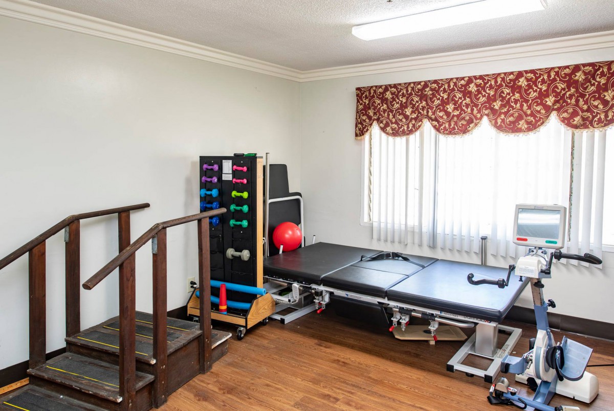 A small gym room with exercise equipment, including a set of dumbbells and a bench.
