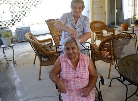 Two elderly women enjoying a haircut outside on the patio.