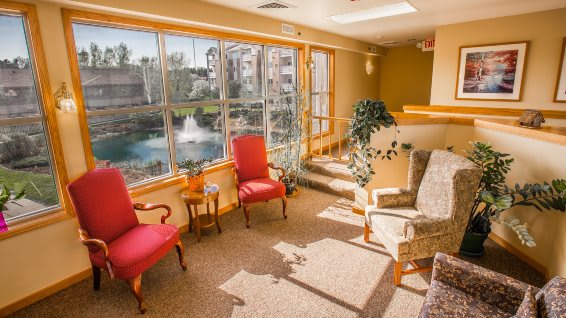 A bright, cozy sitting area with large windows overlooking a fountain and outdoor scenery.