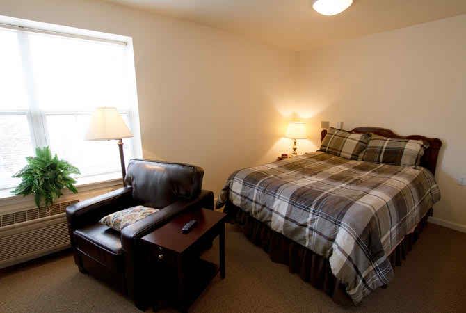 A cozy bedroom with a comfortable armchair and warm lighting.