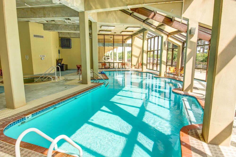 A sunlit indoor swimming pool with floor-to-ceiling windows and modern architecture.