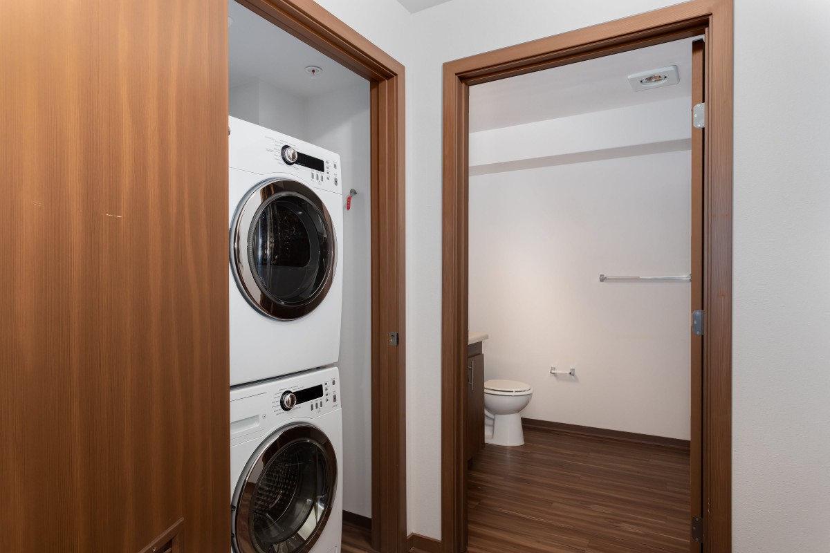 A home interior featuring a stacked washer and dryer next to a bathroom.