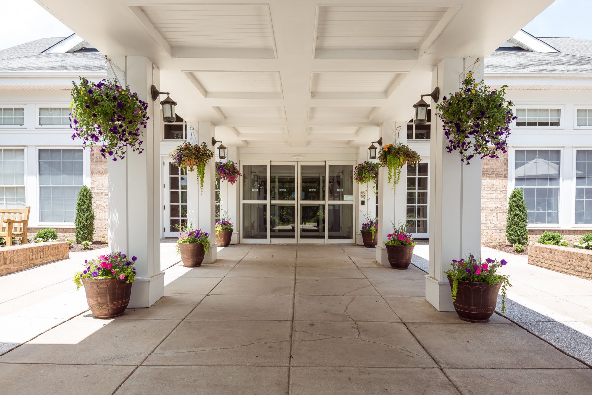 A building entrance with decorative columns and hanging plants.